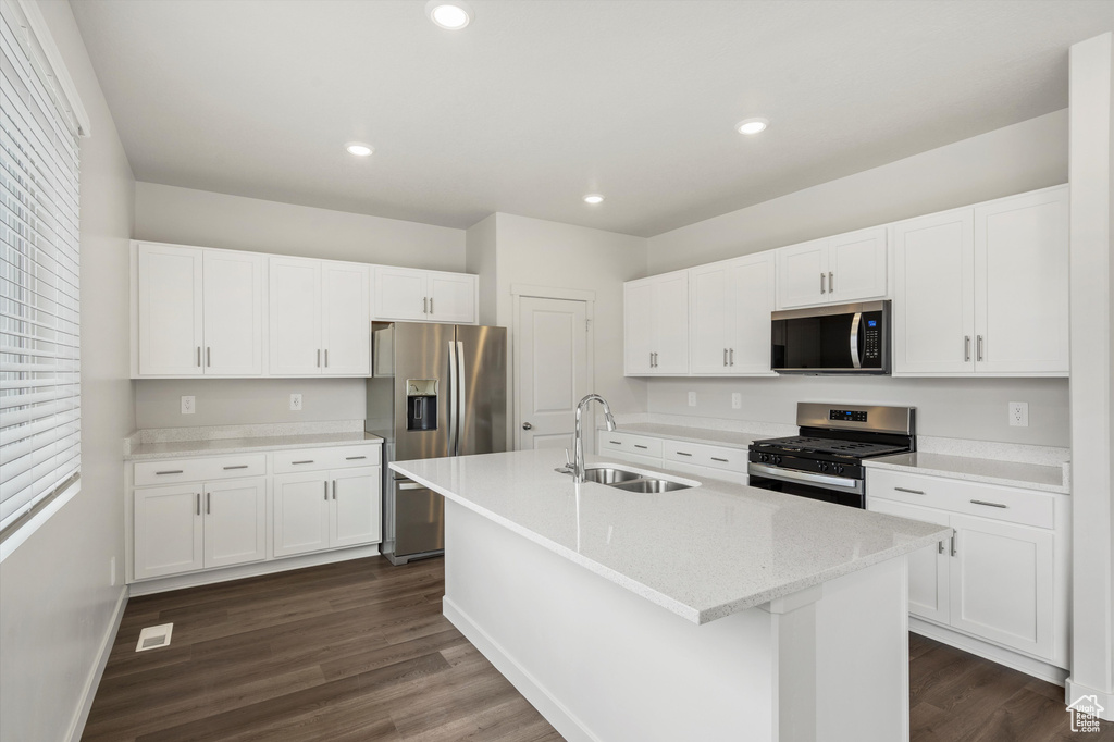 Kitchen featuring appliances with stainless steel finishes, dark wood-style flooring, an island with sink, white cabinetry, and recessed lighting