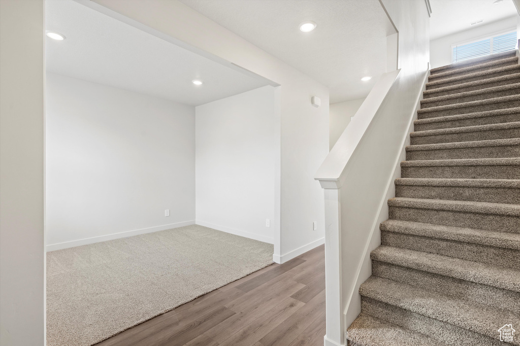Stairway featuring wood finished floors and recessed lighting