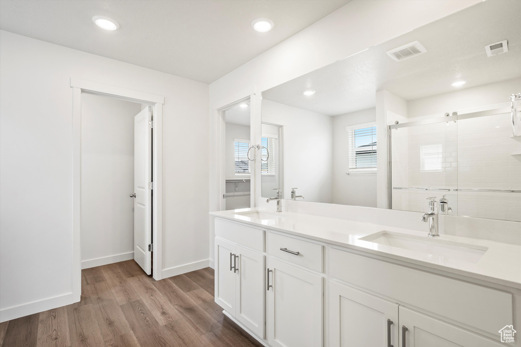 Bathroom with wood finished floors, double vanity, a stall shower, and recessed lighting