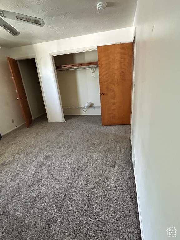 Unfurnished bedroom featuring a textured ceiling, carpet flooring, and ceiling fan