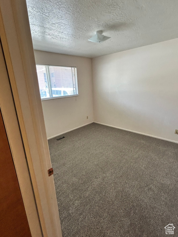 Unfurnished room featuring carpet floors, a textured ceiling, and baseboards
