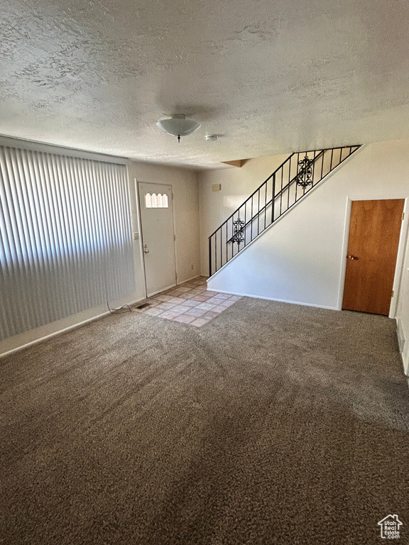 Carpeted entryway with a textured ceiling and stairs