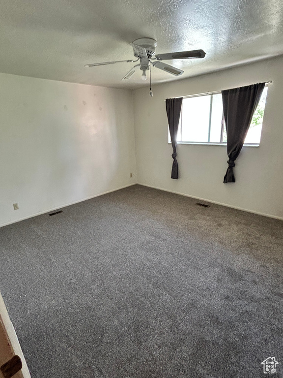 Spare room featuring a textured ceiling, carpet, and ceiling fan