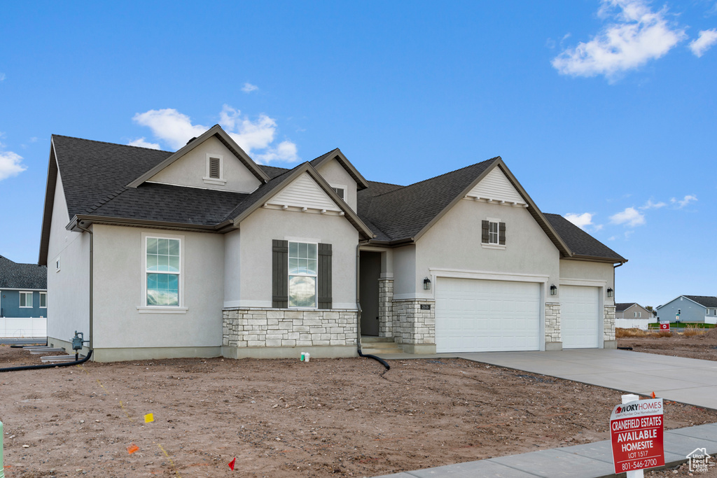 View of front of property with stone siding, stucco siding, driveway, and a shingled roof