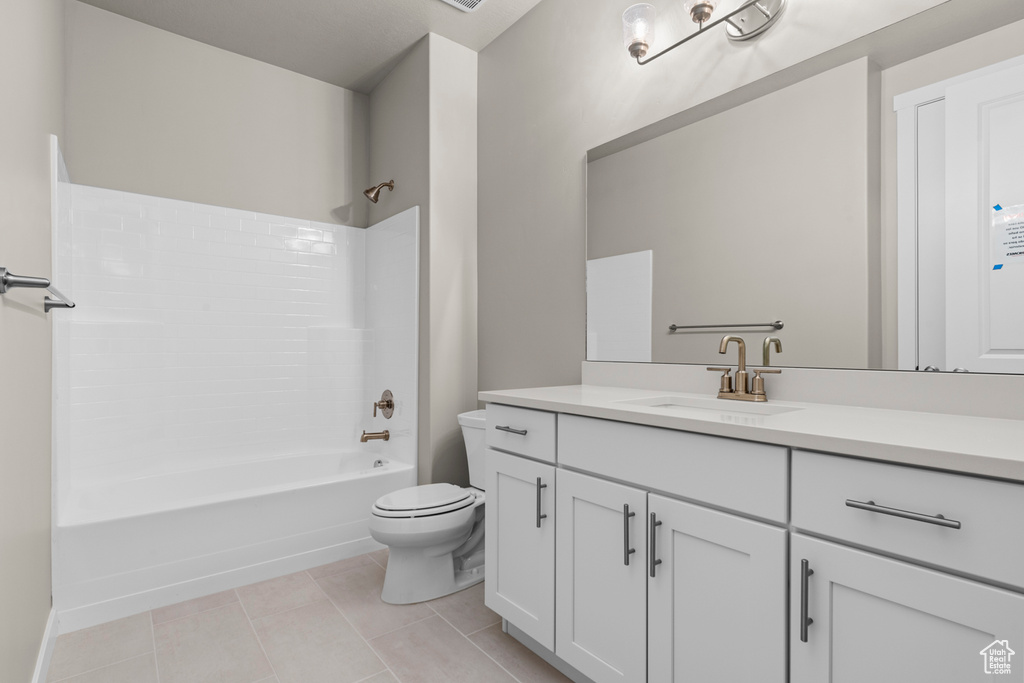 Bathroom with toilet, vanity, tub / shower combination, and tile patterned flooring