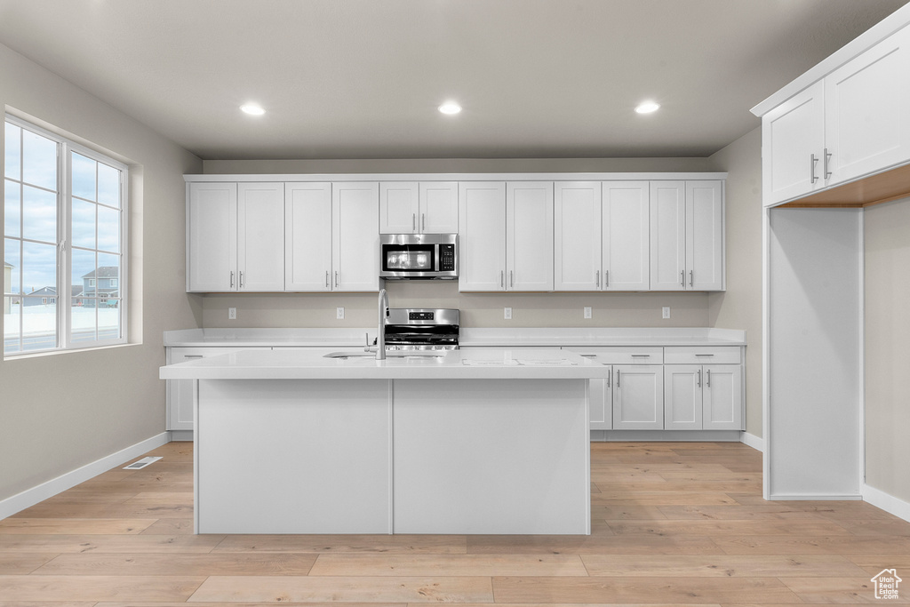 Kitchen with stainless steel appliances, light countertops, baseboards, and recessed lighting