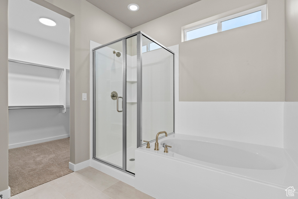 Full bath with a shower stall, a bath, a spacious closet, tile patterned floors, and baseboards