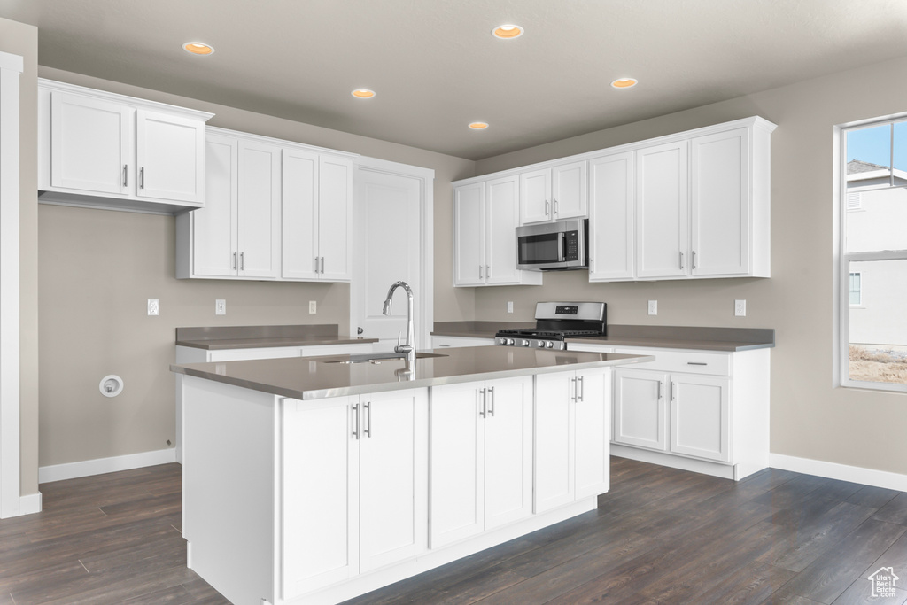 Kitchen with appliances with stainless steel finishes, baseboards, white cabinets, recessed lighting, and a sink