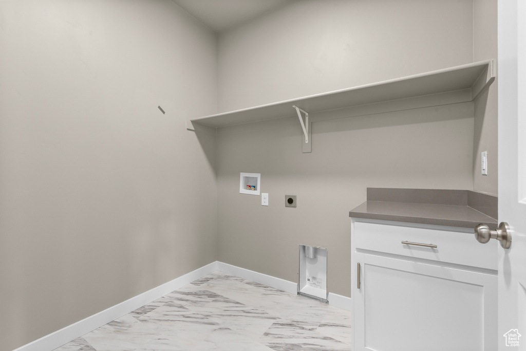 Laundry room featuring electric dryer hookup, light marble finish flooring, washer hookup, baseboards, and cabinet space