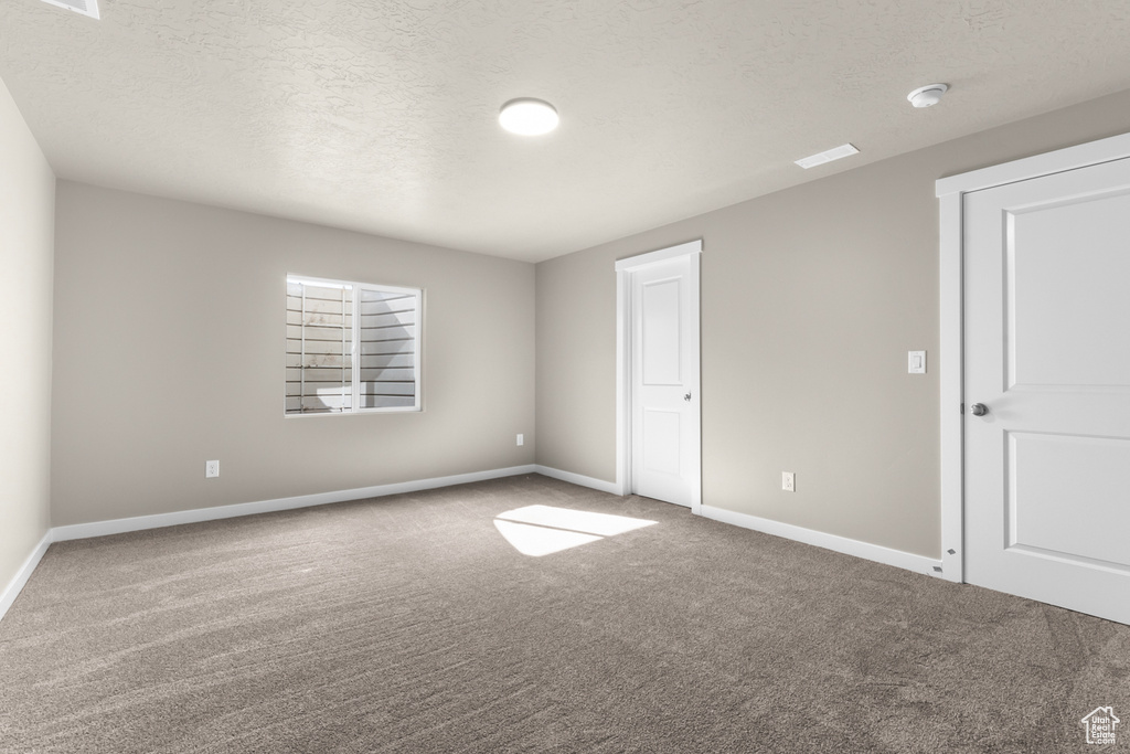 Unfurnished bedroom with carpet flooring, baseboards, and a textured ceiling