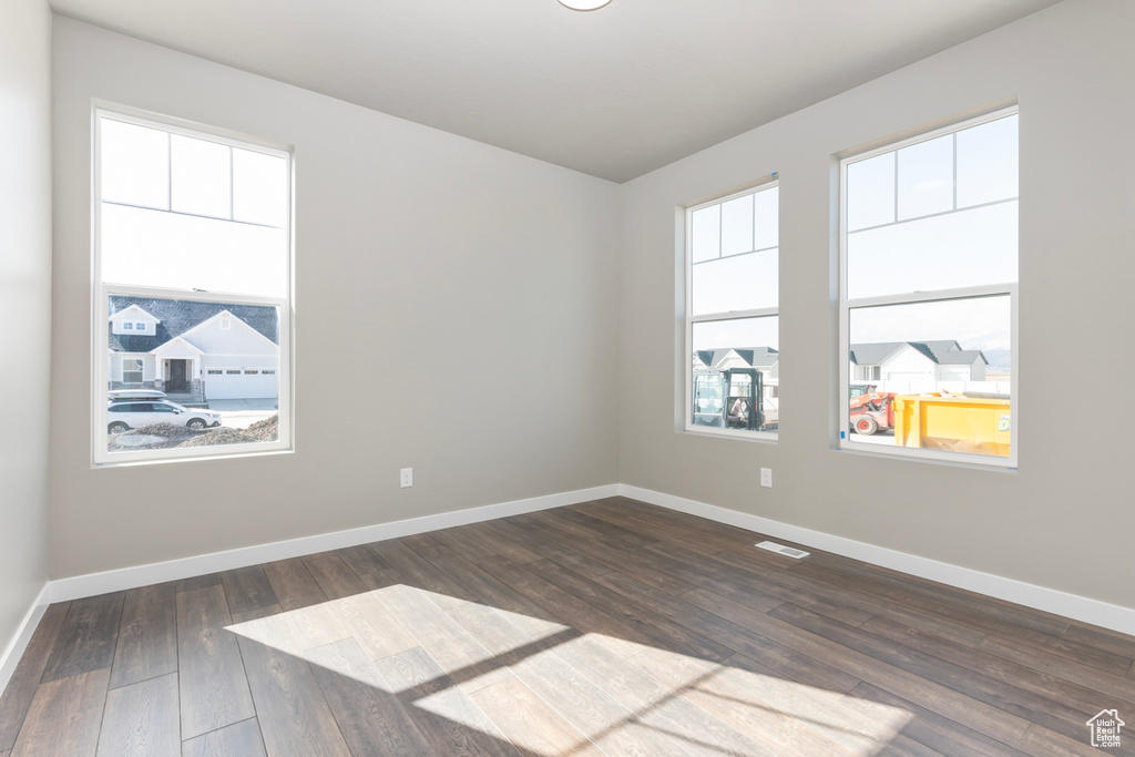 Unfurnished room featuring dark wood-type flooring and baseboards