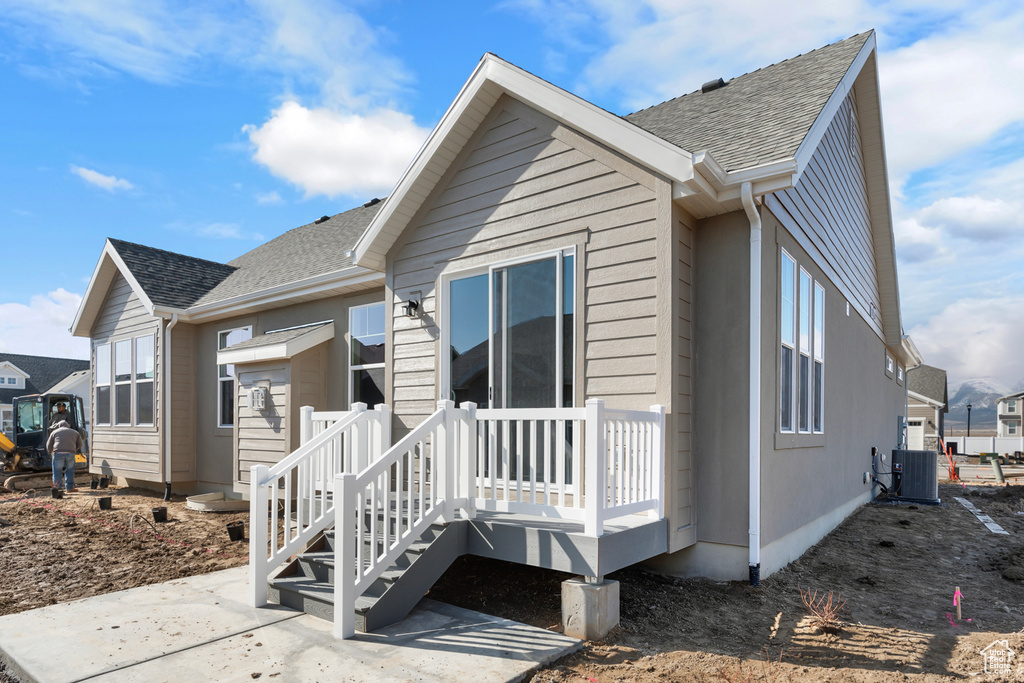 Back of property with central AC, roof with shingles, and a deck