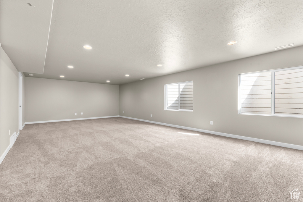 Carpeted spare room featuring recessed lighting, a textured ceiling, and baseboards