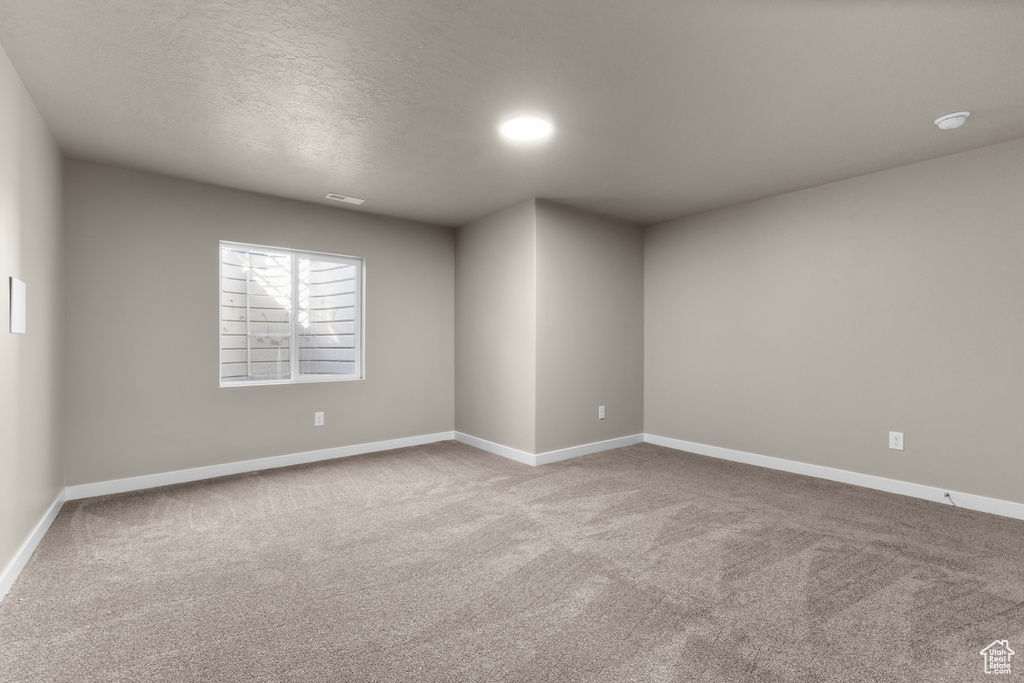 Carpeted spare room with baseboards and a textured ceiling