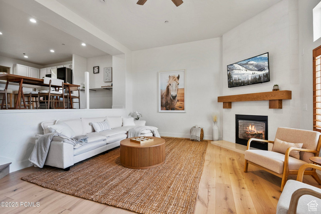 Living area featuring wood finished floors, a large fireplace, a ceiling fan, recessed lighting, and baseboards