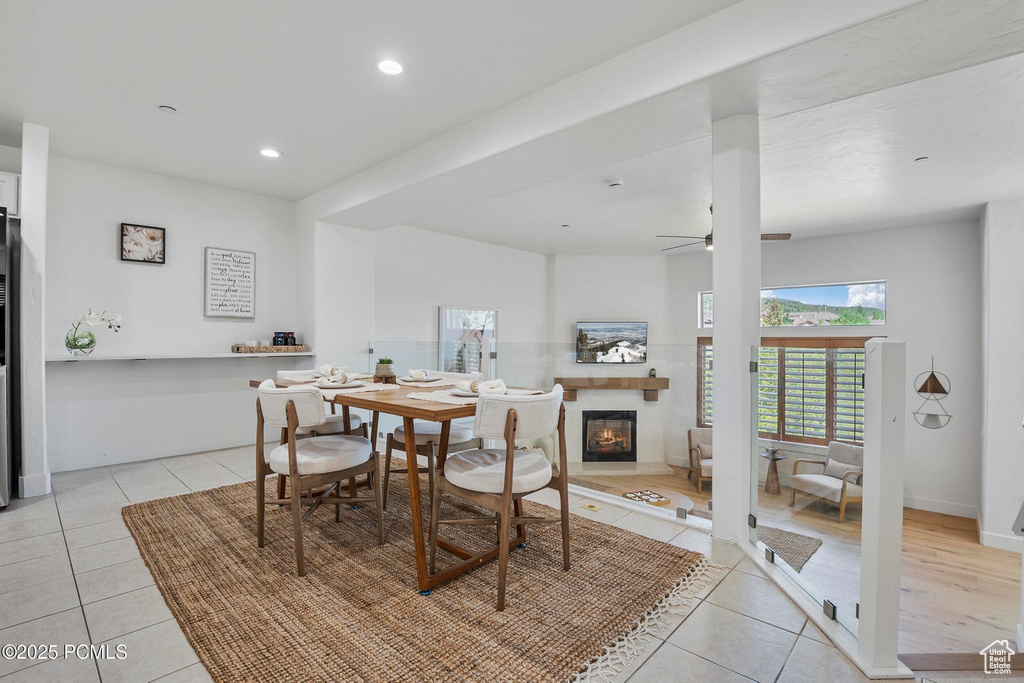 Dining room featuring light tile patterned floors, ceiling fan, a glass covered fireplace, recessed lighting, and baseboards