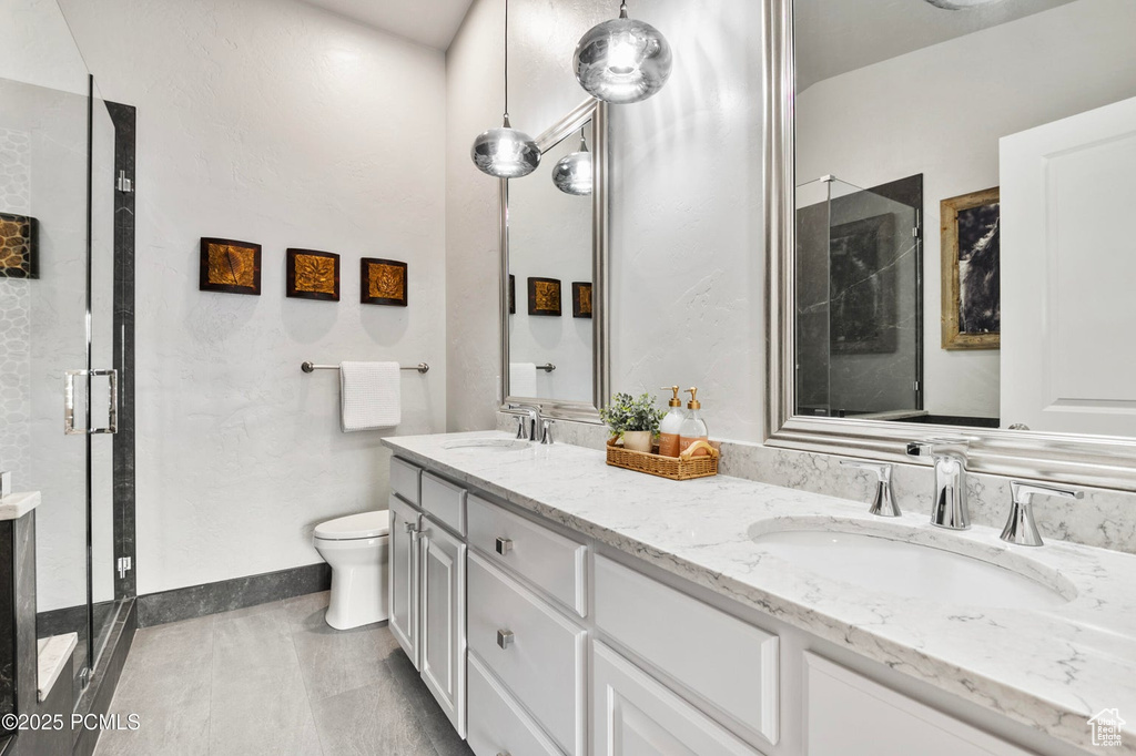 Bathroom with a shower stall, double vanity, and toilet