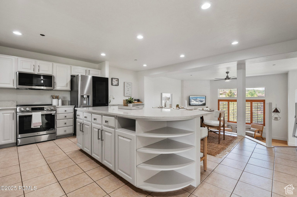 Kitchen featuring stainless steel appliances, open shelves, light tile patterned floors, a ceiling fan, and white cabinets