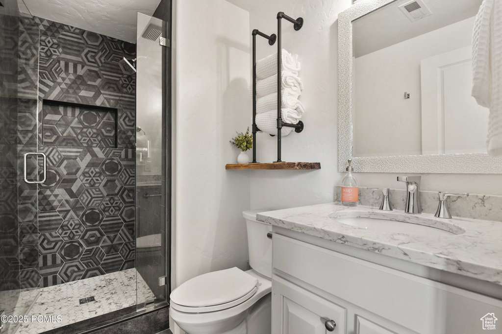 Bathroom with vanity, toilet, and a stall shower