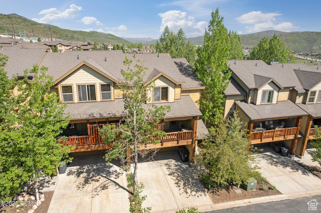 View of front of property with a mountain view, driveway, a residential view, and a shingled roof