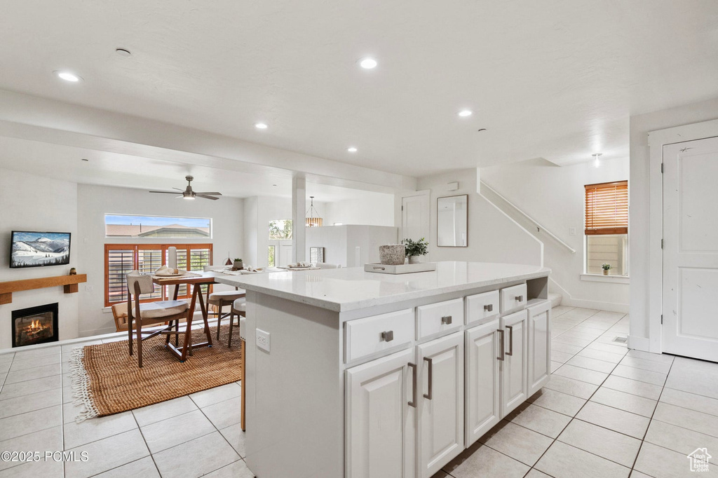 Kitchen featuring light tile patterned floors, a glass covered fireplace, recessed lighting, open floor plan, and a kitchen island