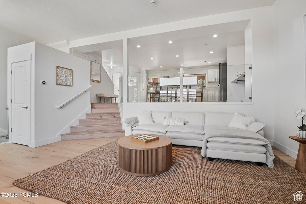 Living room with light wood-style floors, stairs, recessed lighting, and baseboards