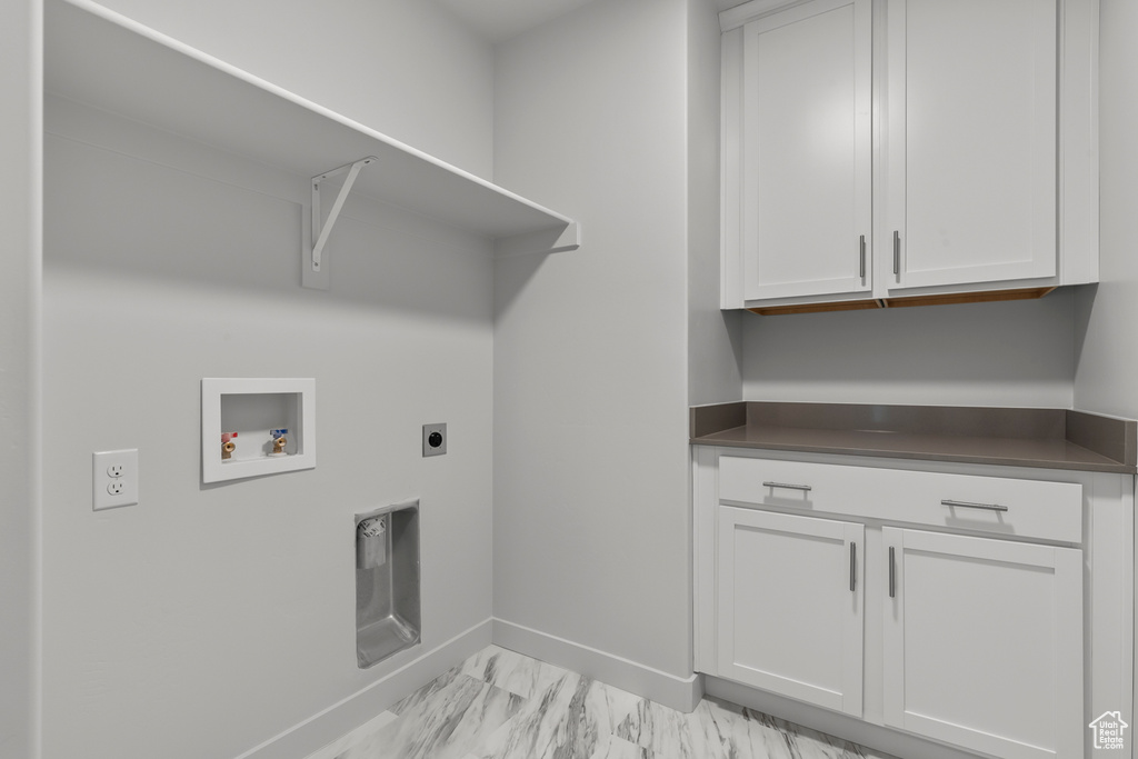 Laundry area with cabinet space, washer hookup, baseboards, hookup for an electric dryer, and light marble finish flooring
