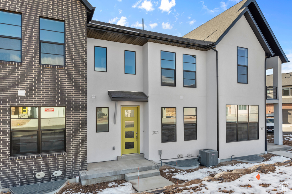 Townhome / multi-family property featuring stucco siding, central air condition unit, and brick siding