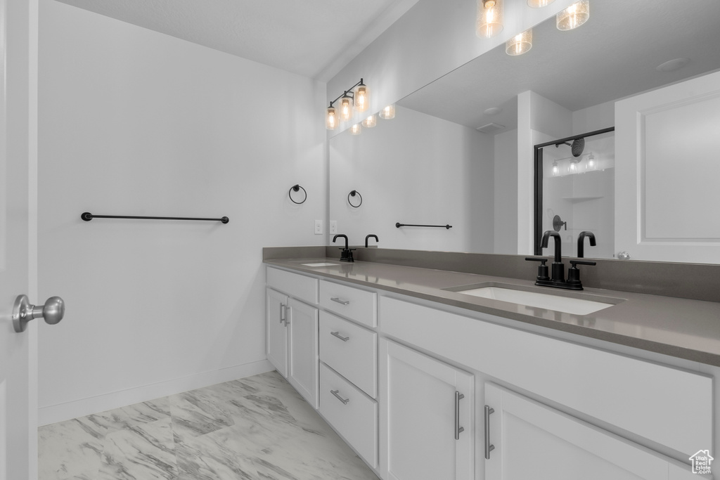 Full bathroom with marble finish flooring, double vanity, an enclosed shower, and baseboards