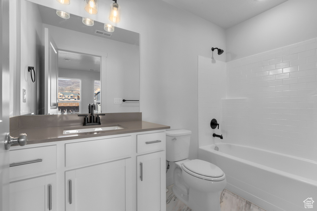 Bathroom with toilet, vanity, and  shower combination