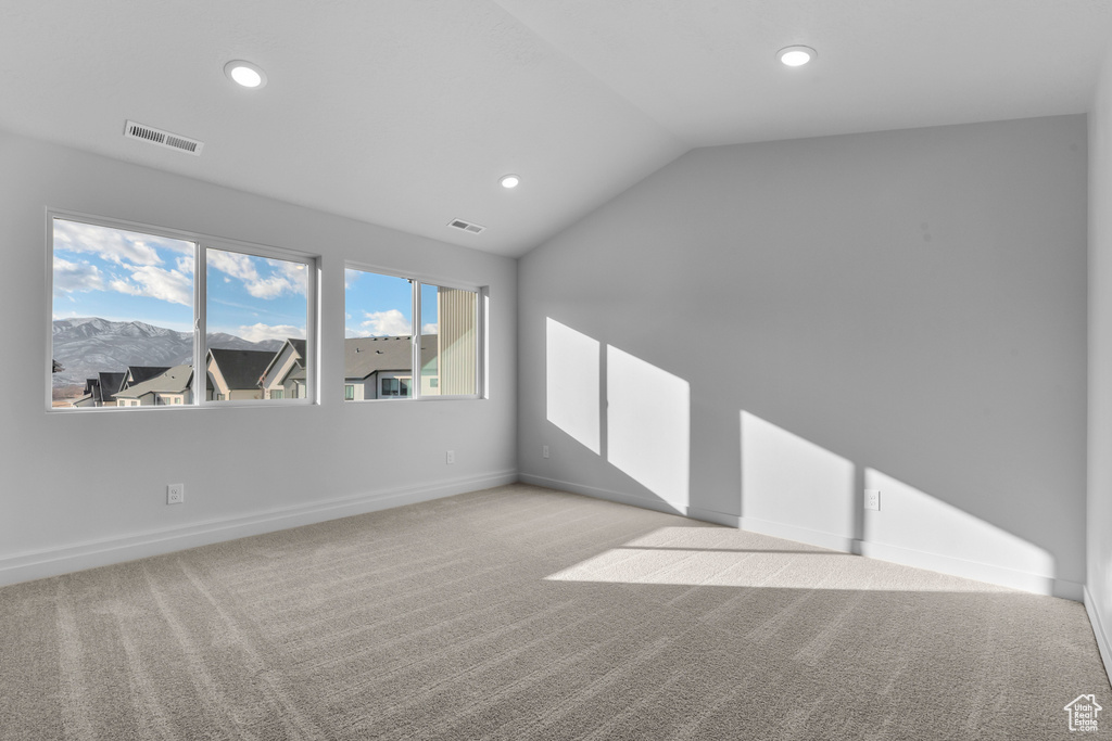 Carpeted empty room featuring vaulted ceiling, recessed lighting, and baseboards