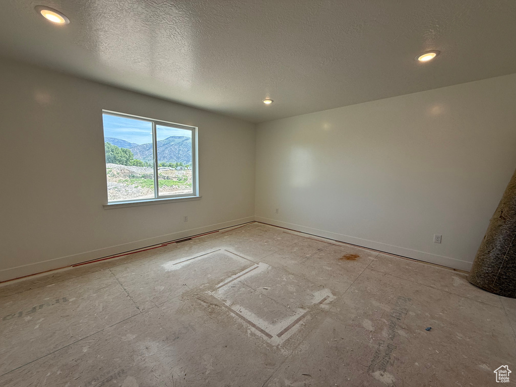 Unfurnished room featuring a textured ceiling, baseboards, and recessed lighting