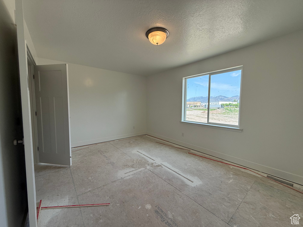 Unfurnished room featuring a textured ceiling and baseboards