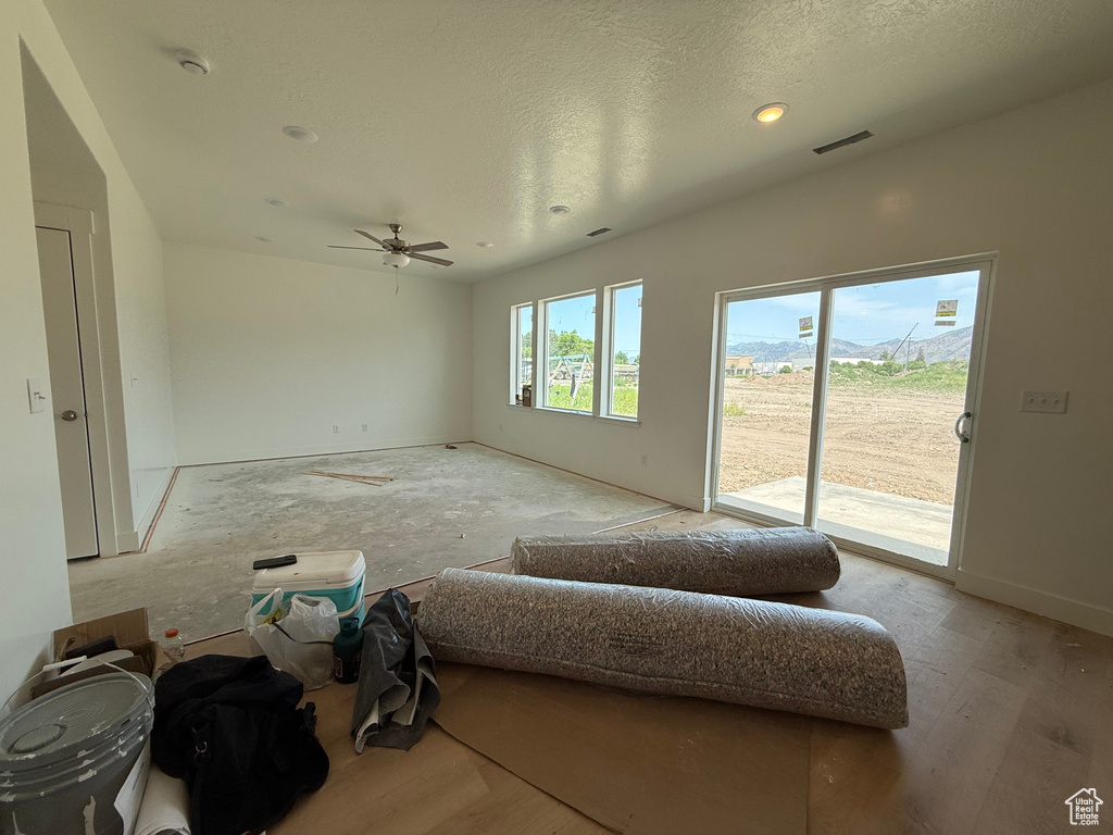 Unfurnished living room with a ceiling fan, wood finished floors, a textured ceiling, and recessed lighting