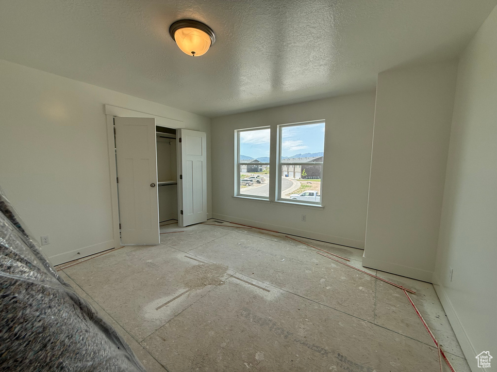 Unfurnished bedroom featuring a closet, baseboards, and a textured ceiling