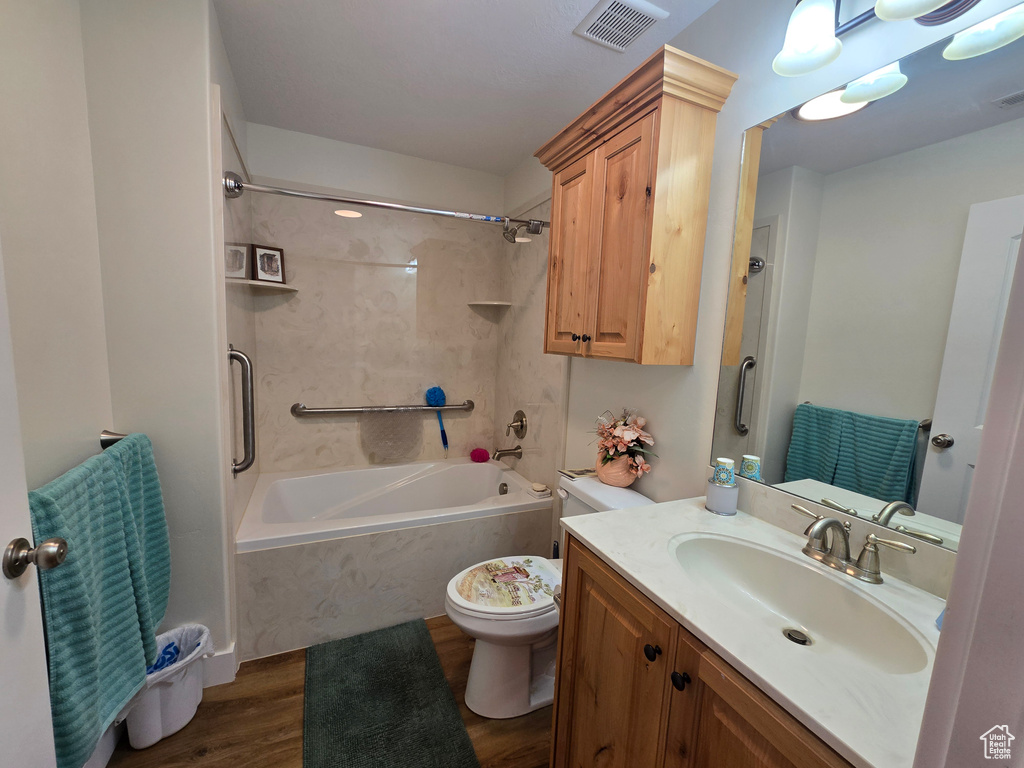 Full bath featuring bathing tub / shower combination, toilet, wood finished floors, and vanity