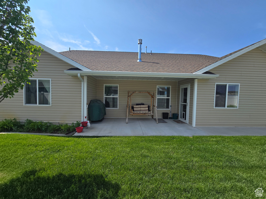 Back of property with a lawn, a patio, and roof with shingles