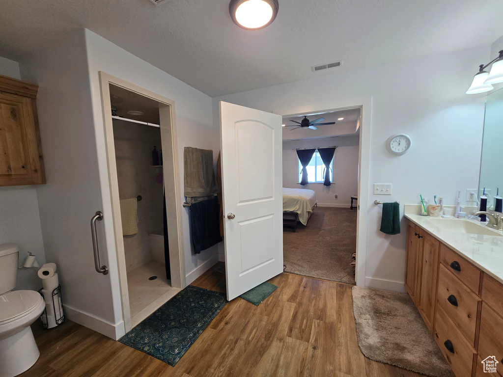 Ensuite bathroom featuring toilet, wood finished floors, a shower stall, and vanity