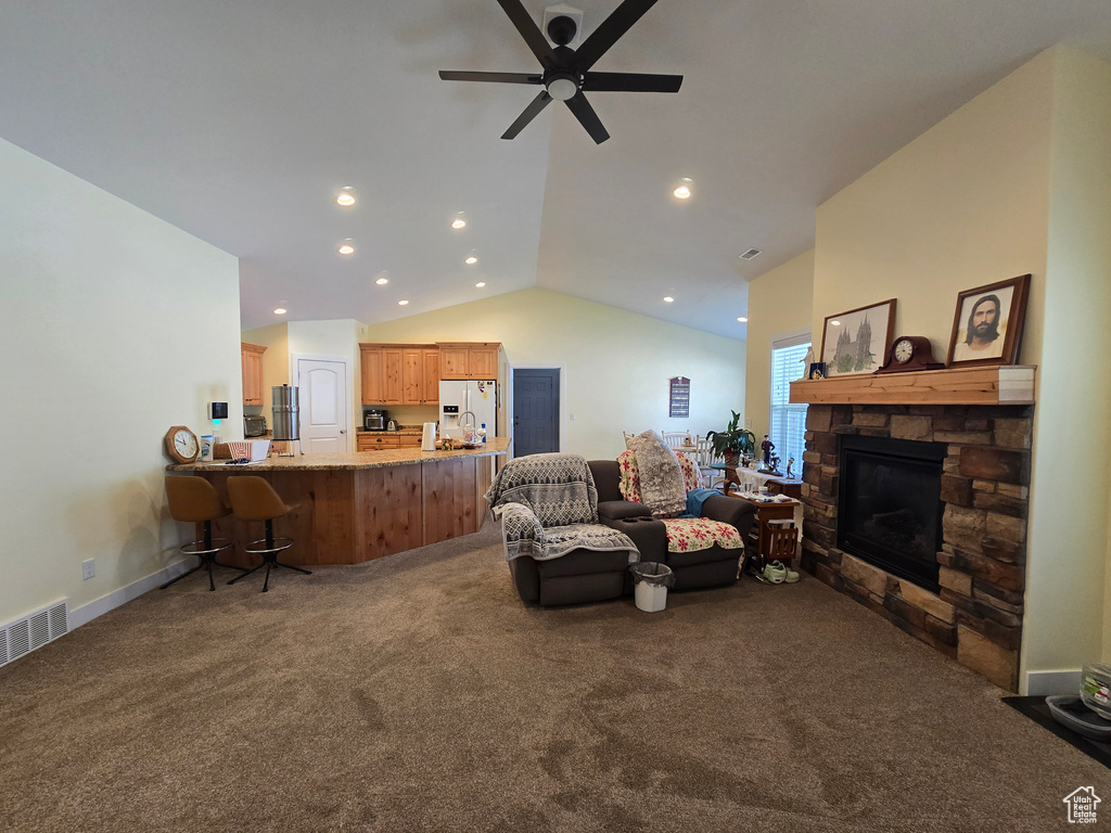 Living room with carpet floors, lofted ceiling, a ceiling fan, a stone fireplace, and recessed lighting