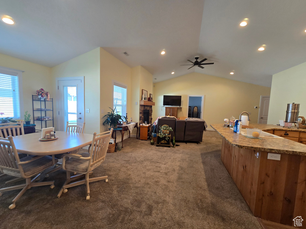 Dining room featuring lofted ceiling, light carpet, a fireplace, ceiling fan, and recessed lighting