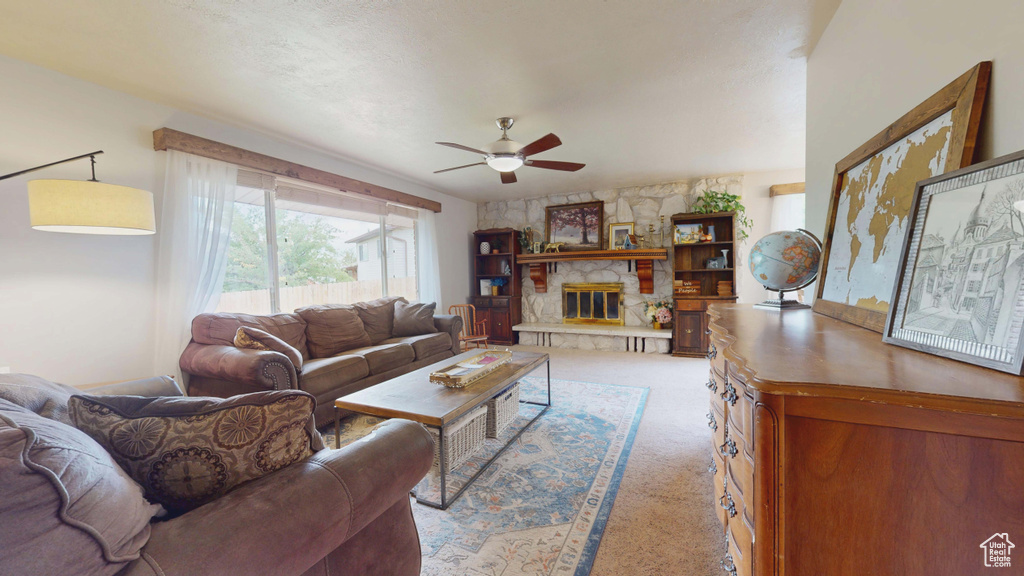 Carpeted living room featuring ceiling fan and a fireplace