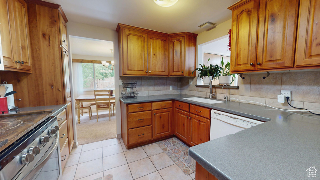 Kitchen with a sink, stainless steel electric range, white dishwasher, and brown cabinetry