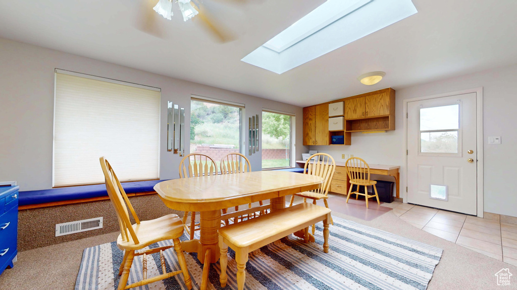 Dining room featuring a skylight, a ceiling fan, and light tile patterned floors