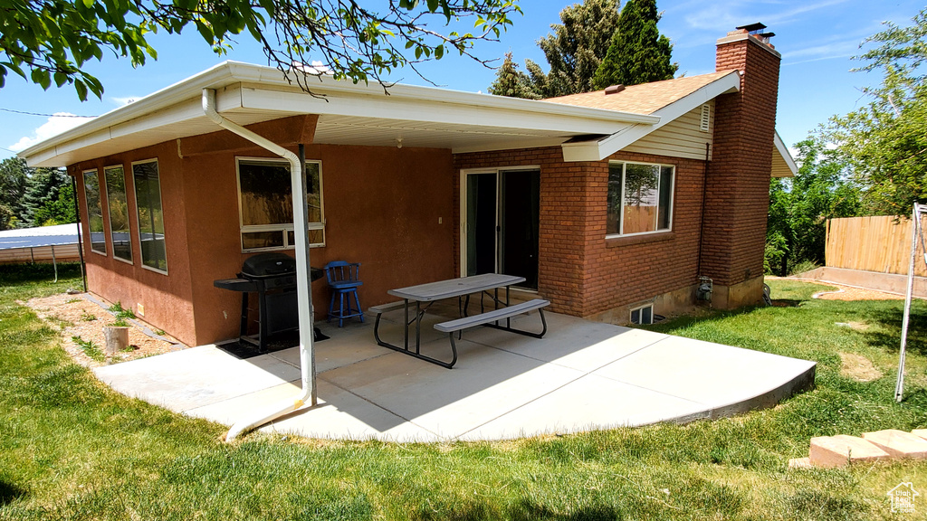 Rear view of property featuring a chimney, a patio area, and brick siding