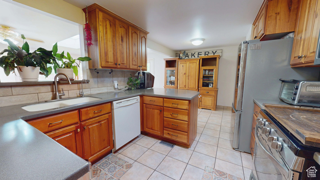 Kitchen with dishwasher, a sink, stainless steel electric range, a peninsula, and brown cabinets