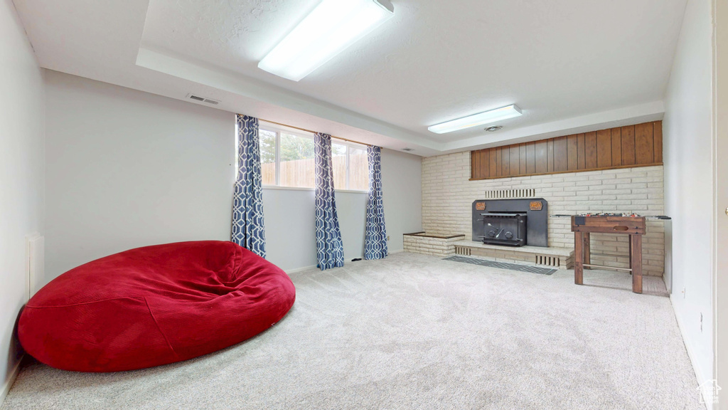 Sitting room featuring a brick fireplace, carpet flooring, baseboards, and a raised ceiling