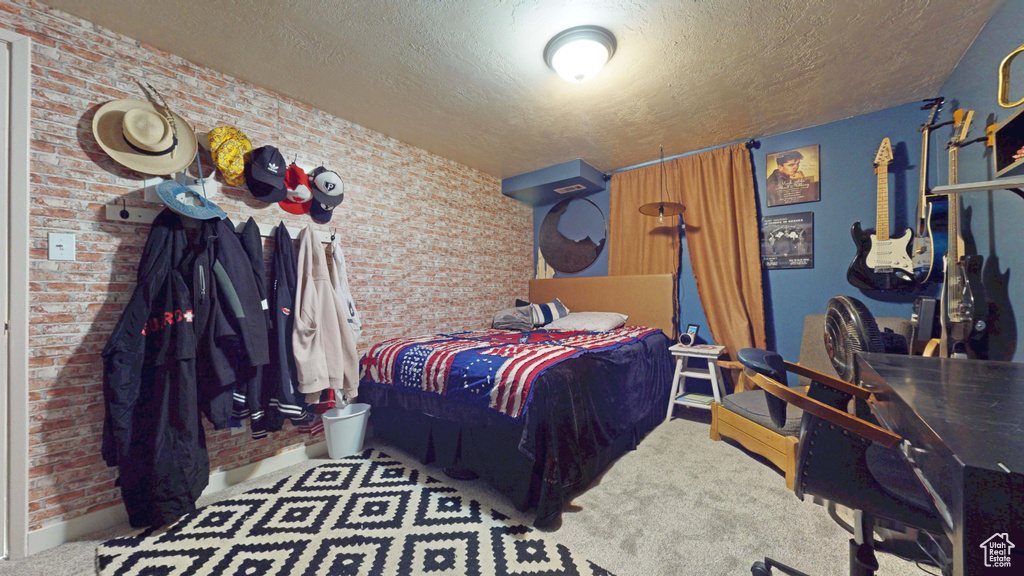 Bedroom with brick wall, a textured ceiling, baseboards, and carpet flooring