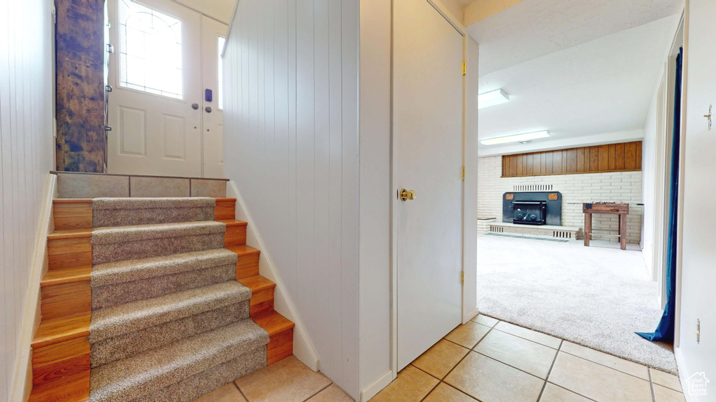 Stairway featuring tile patterned floors, carpet floors, and a wood stove