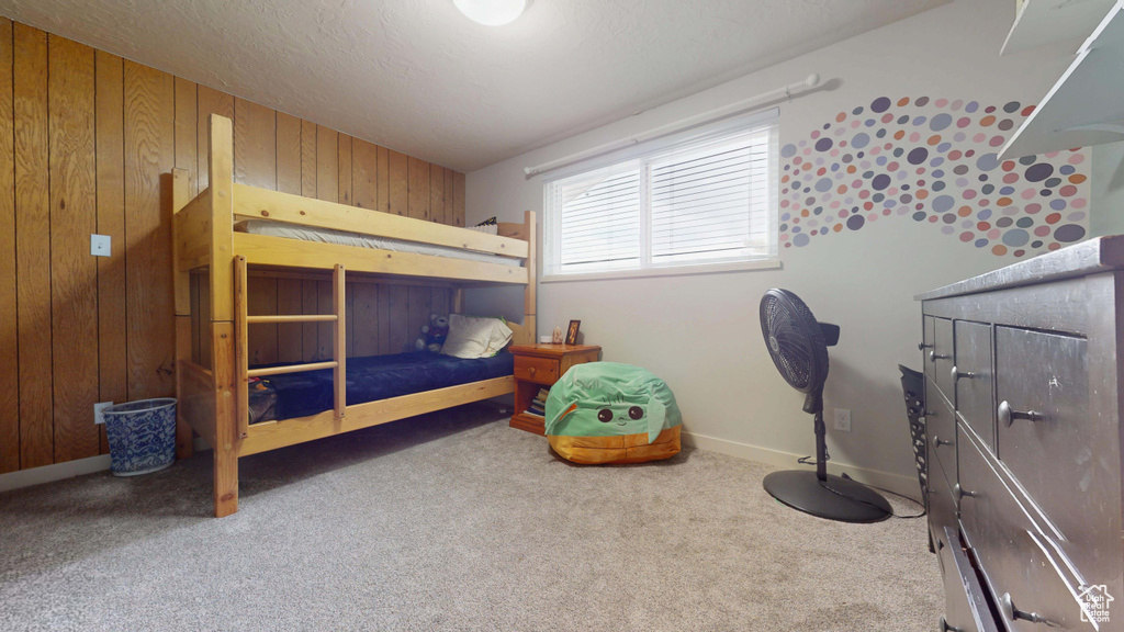 Bedroom featuring wood walls, carpet flooring, and baseboards