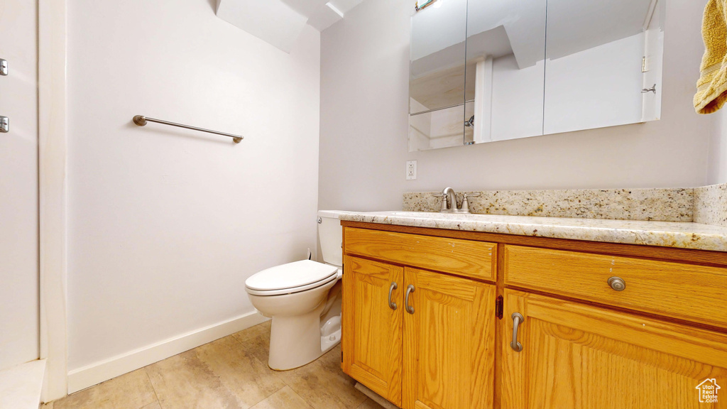 Full bathroom with vanity, toilet, and baseboards